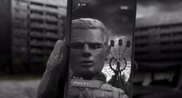 Le reflet d'un homme apparaît sur un écran de smartphone (derrière lui, on aperçoit une grande roue)
